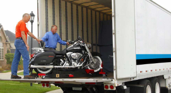 back of truck with 2 drivers loading a motorcycle